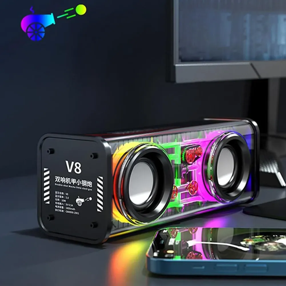Compact transparent Bluetooth speaker with dual drivers and vivid RGB lighting on a dark desktop, with a smartphone in the foreground.