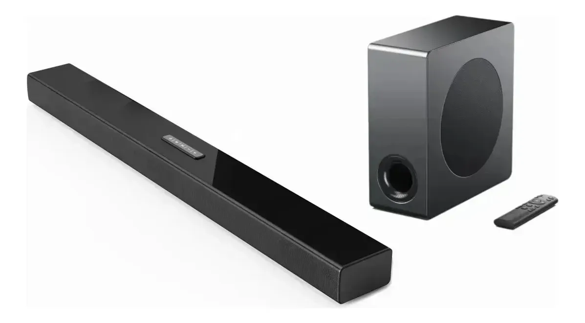 Slim black soundbar with a separate wireless subwoofer and remote control against a white background.