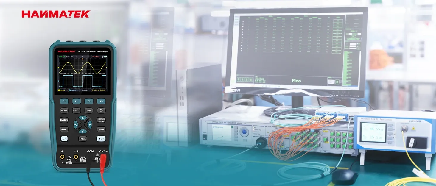 Compact handheld Haimatek HO525 portable oscilloscope with waveform display, shown in a blurred industrial test lab environment with electronic test equipment and monitors in the background.