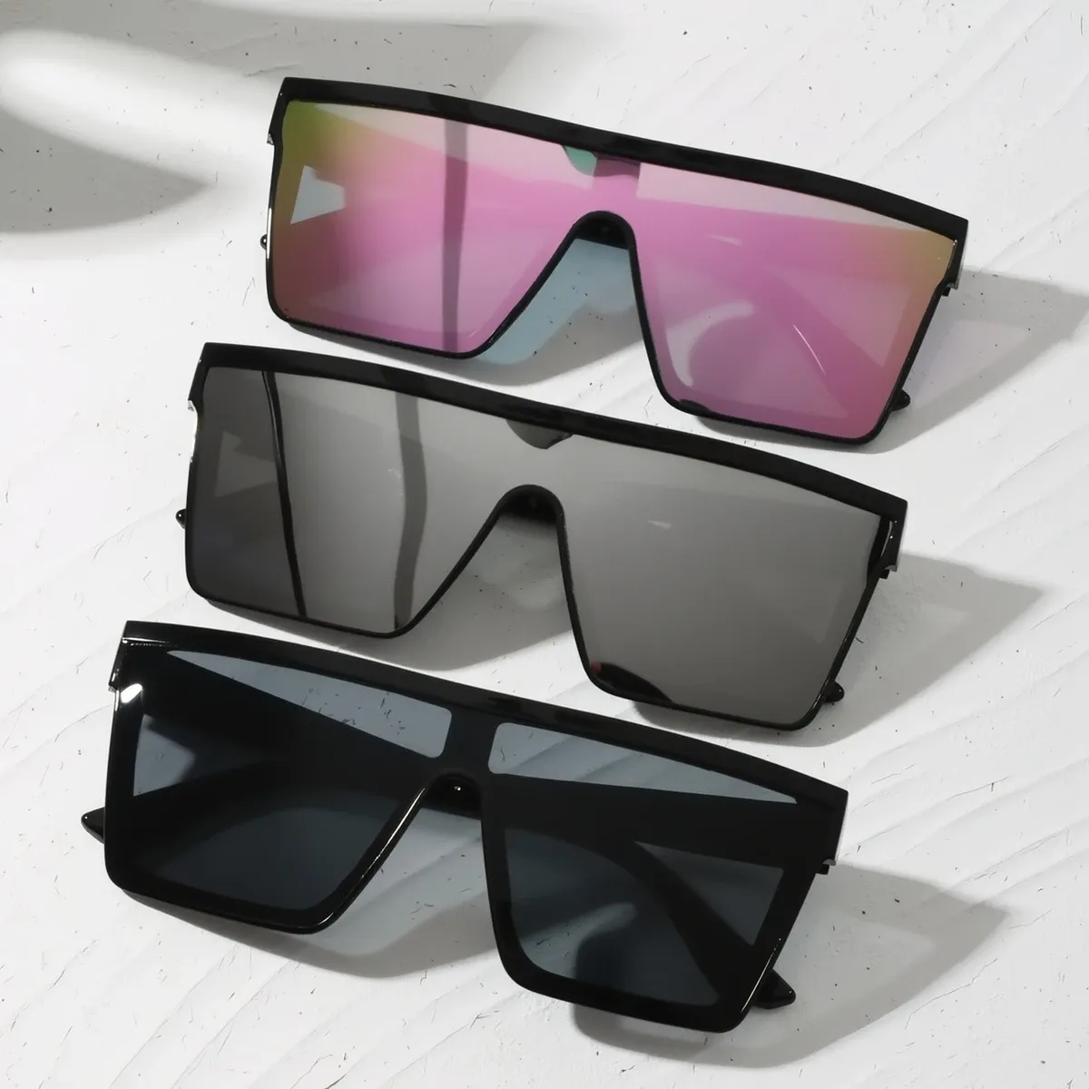 Three pairs of bold statement sunglasses in various shades, displayed on a clean white backdrop, showcasing summer style.