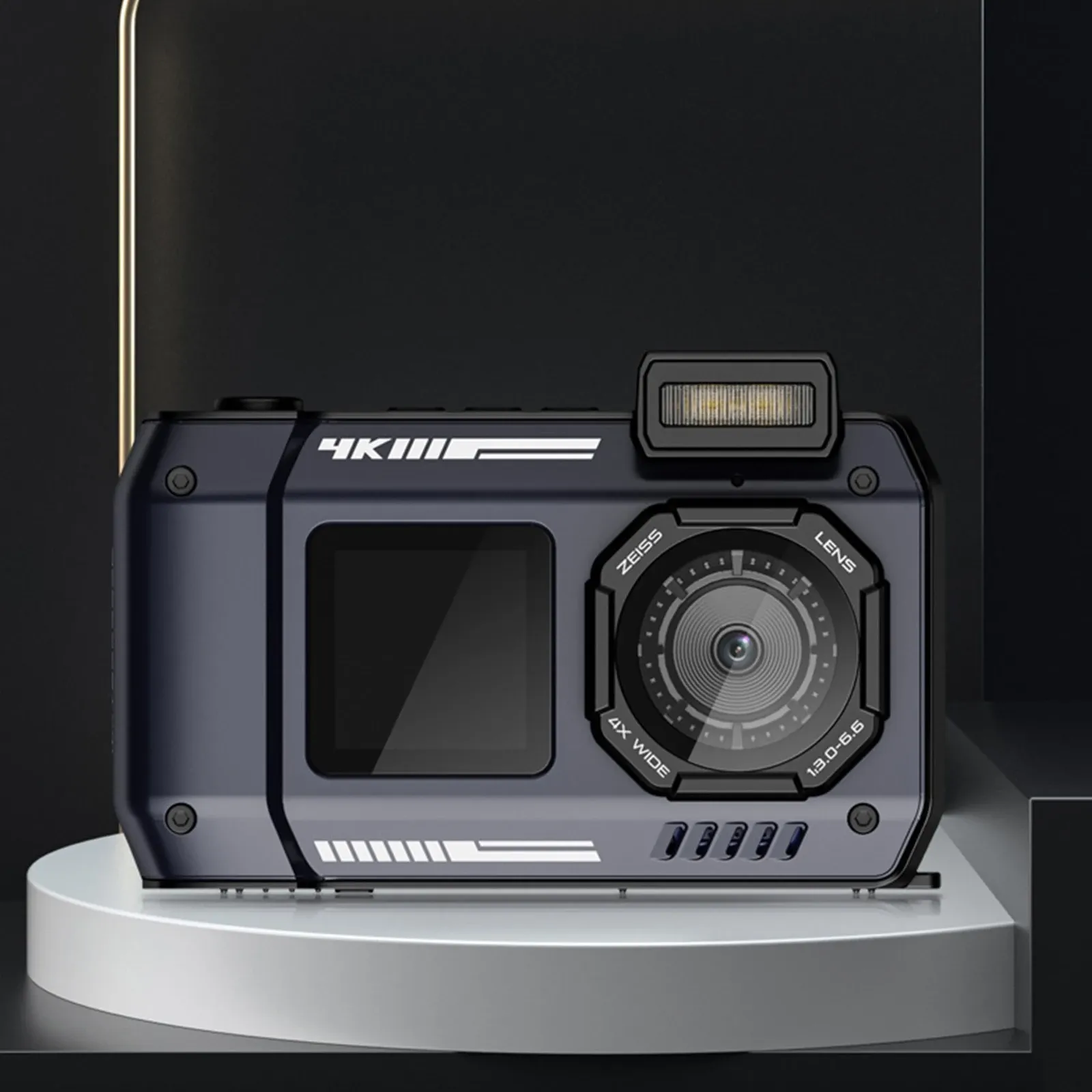 Compact digital camera shown front-facing on a dark studio pedestal with a flash unit and large lens